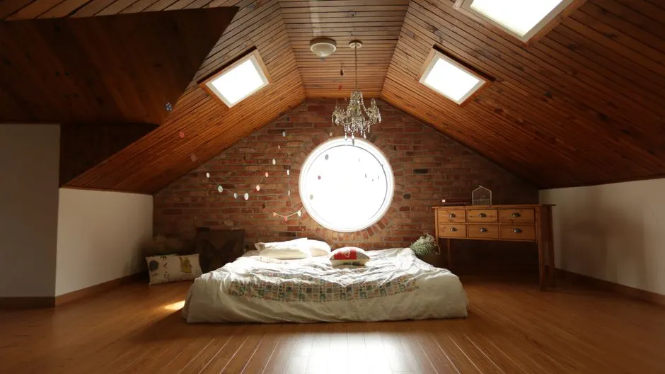 A warm and inviting attic bedroom featuring a unique brick wall and wooden ceiling design.